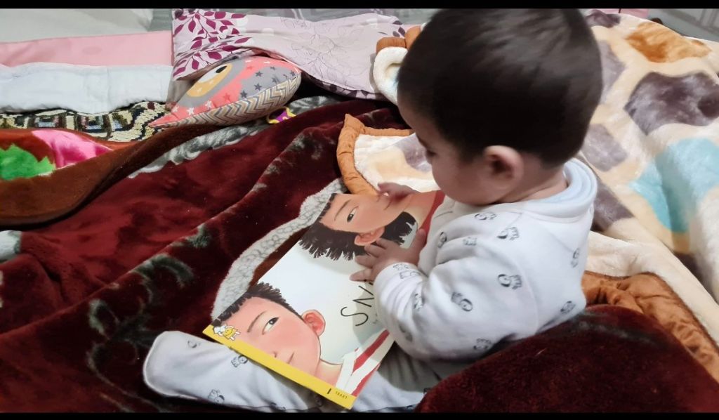 One of Surendra's twin boys — Aarav or Aarush — sitting with a picture book, completely absorbed
